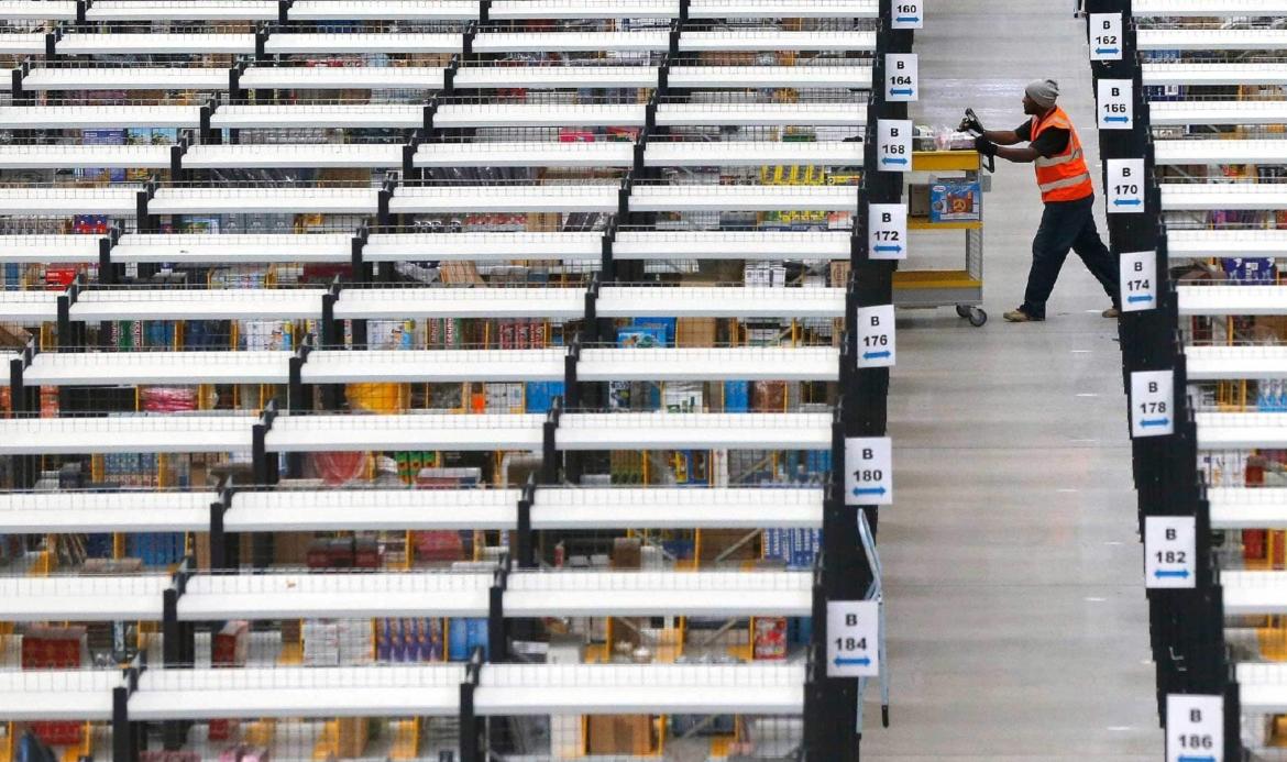 Worker scanning items in a vast warehouse with multiple aisles of shelving.