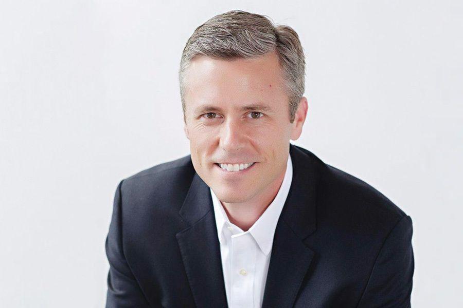 Man in a suit smiling at the camera against a white background.