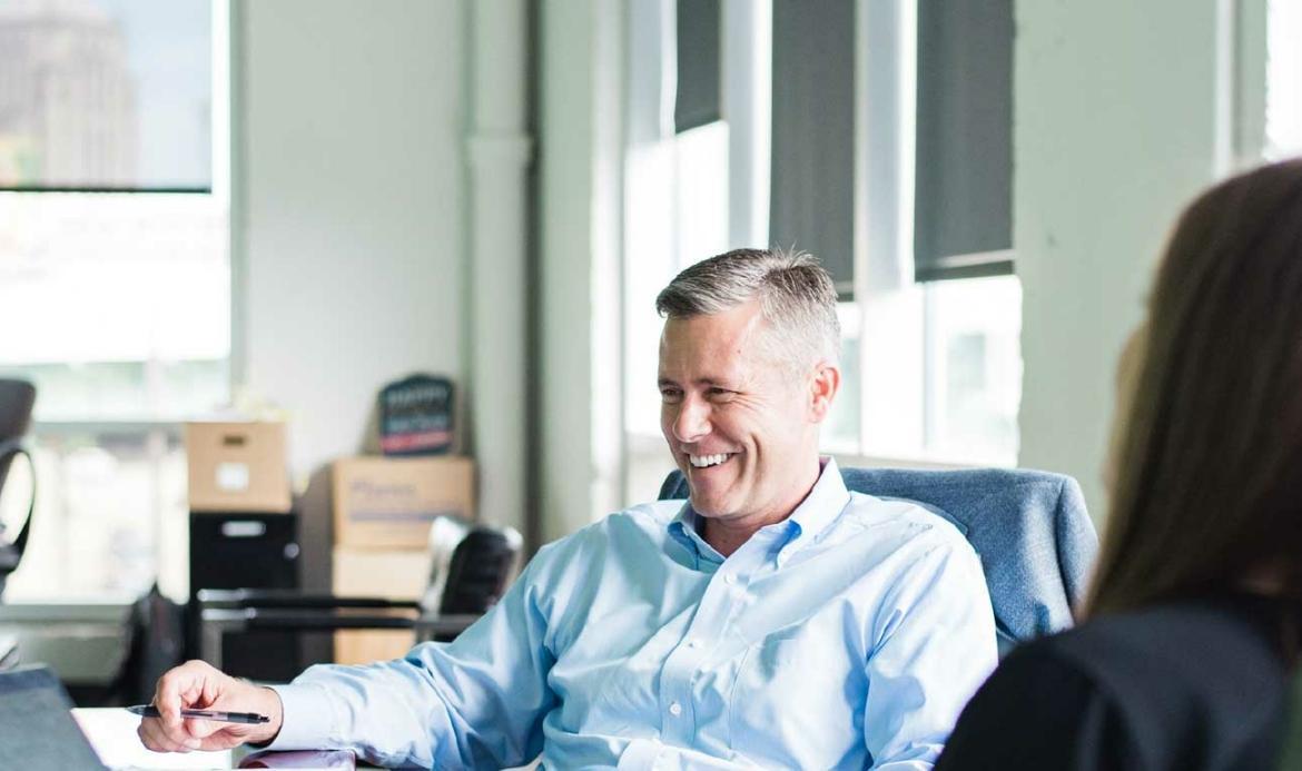 Three professionals engaged in a discussion in a bright office setting.