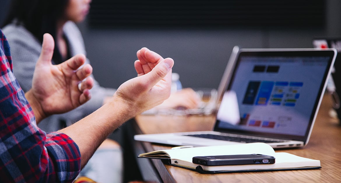 Professional discussion at a work table with a laptop and mobile phone in view, focusing on mastering Q4 advertising strategy.