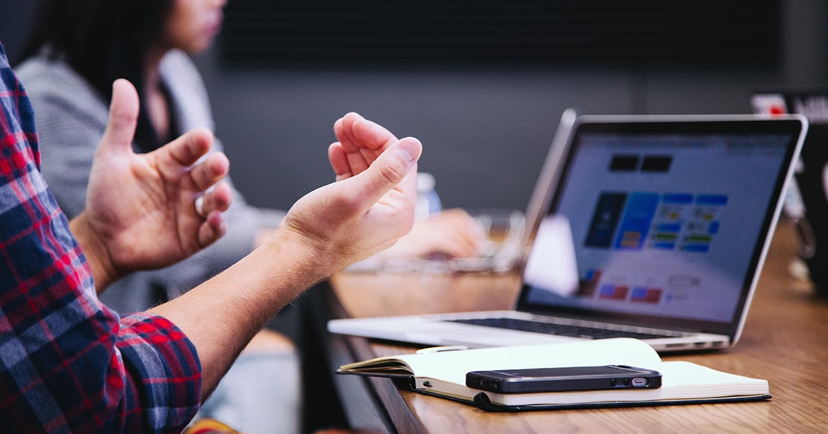 Professional discussion at a work table with a laptop and mobile phone in view, focusing on mastering Q4 advertising strategy.