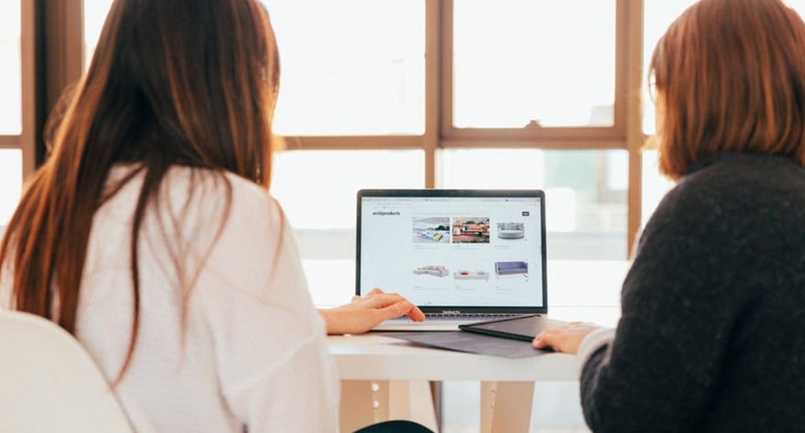 Two individuals mastering Q4 collaborate over a laptop in a bright office setting.