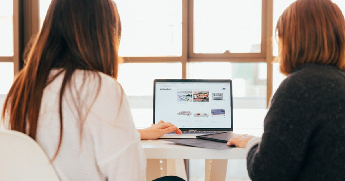 Two individuals mastering Q4 collaborate over a laptop in a bright office setting.