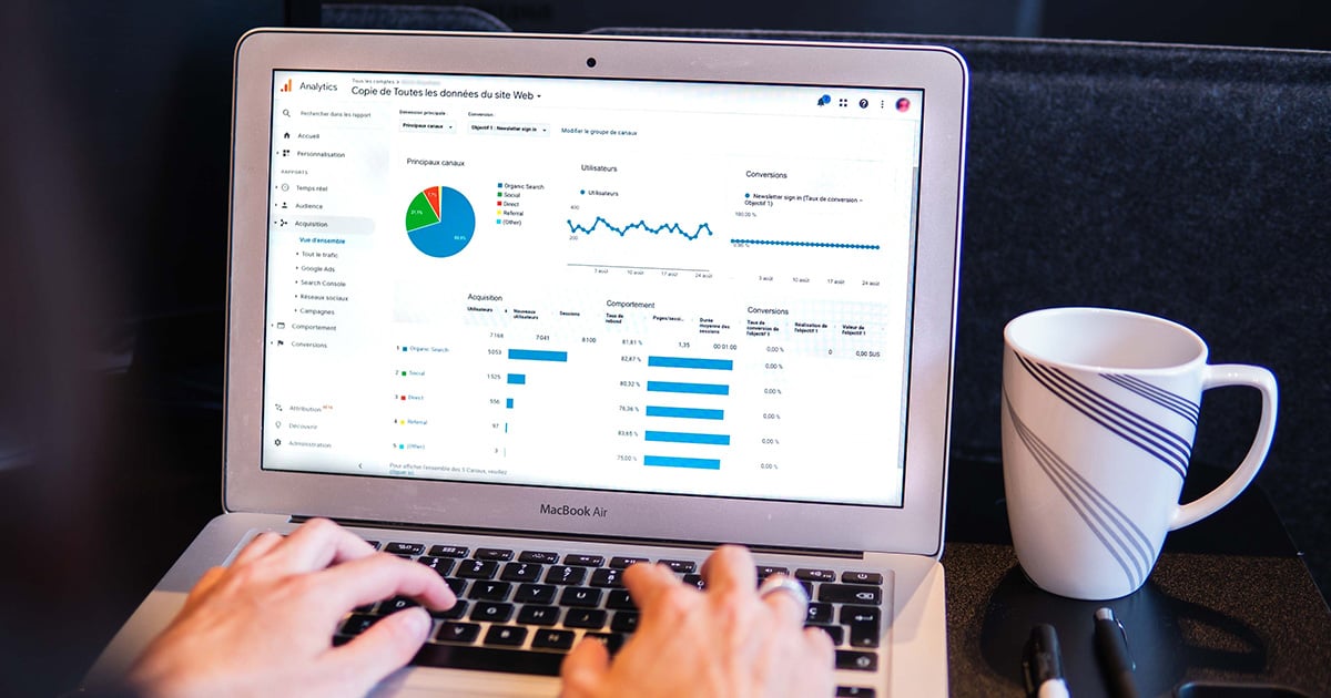 Person analyzing website analytics on a laptop with a cup of coffee on the side, focusing on Fulfillment by Amazon during the holiday season.